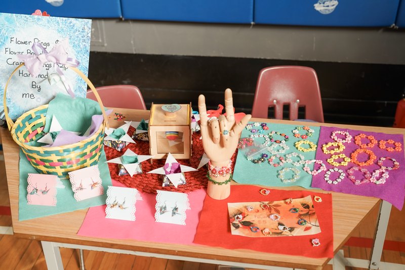 Handmade flower rings and crane earrings at a student craft table